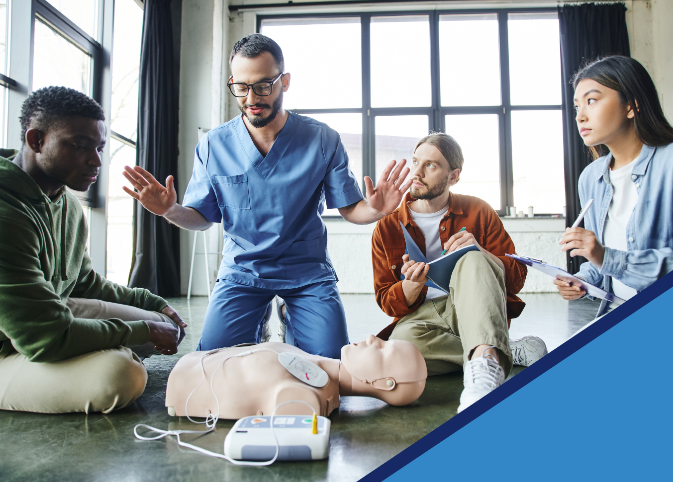 About Us Instructor explaining steps to CPR to a group of three students. A student directly to the instructor's left is taking notes while they learn about CPR taught by Plexsum Testing.