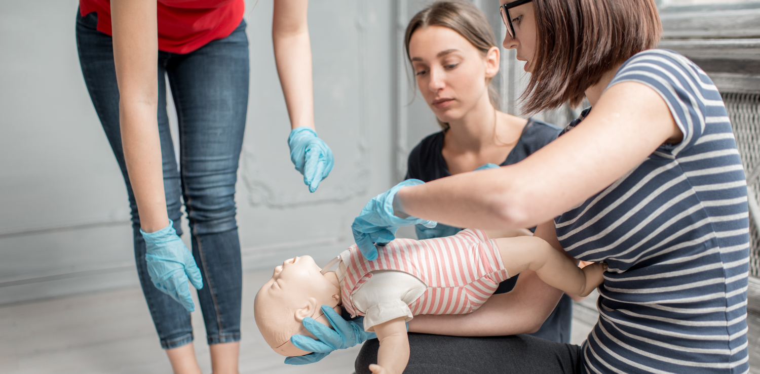 Heartsaver Pediatric First Aid, CPR, AED Instructors teaching community members about basic first aid and CPR for infants and children by practicing with an infant mannequin.