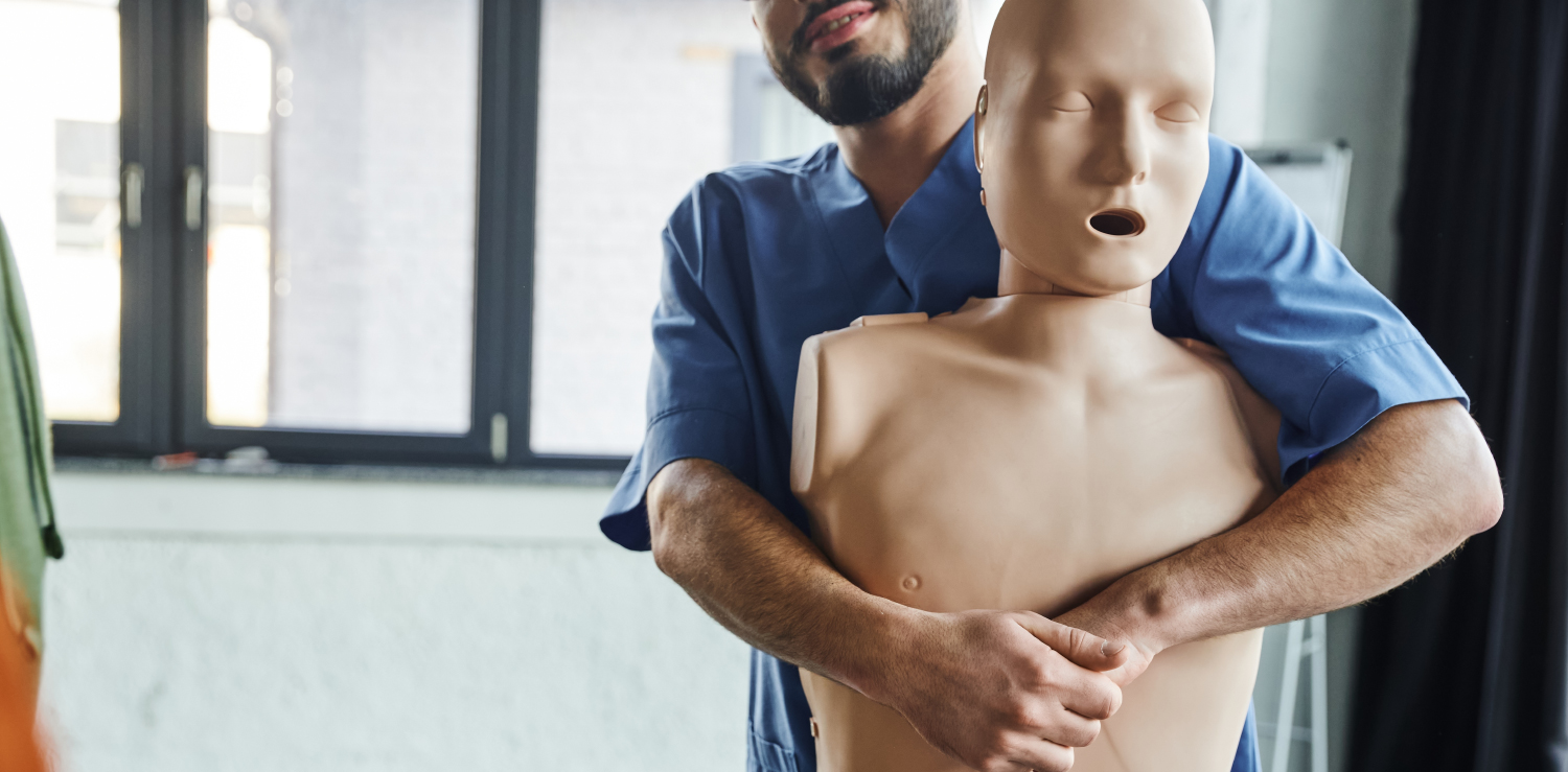 Heartsaver First Aid, CPR, AED for Healthcare A healthcare professional demonstrating on a CPR mannequin how to help prevent choking with the heimlich maneuver, part of the Heartsaver First Aid course.